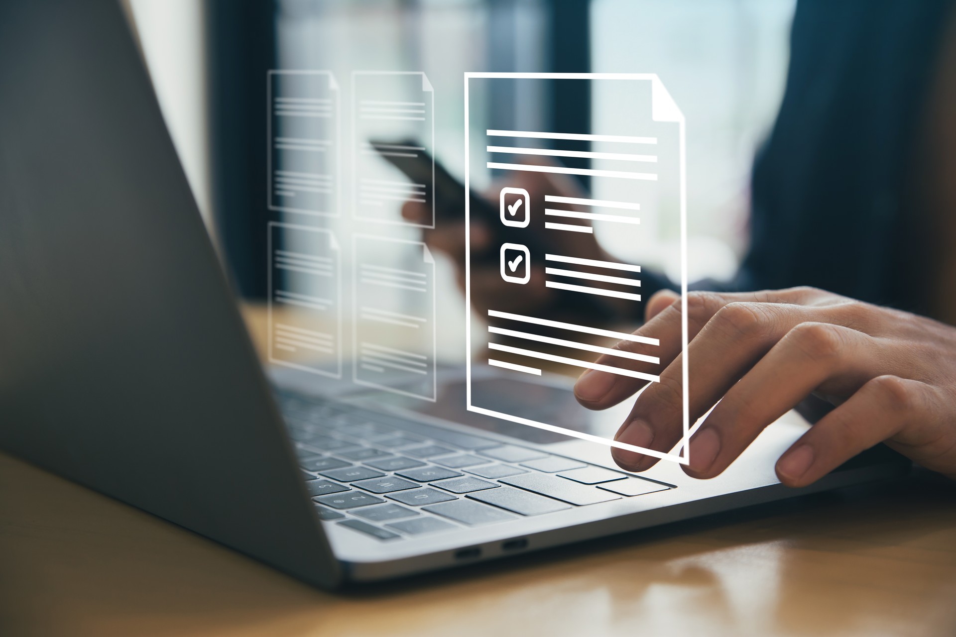 Hand of man using laptop with documents with checkbox lists